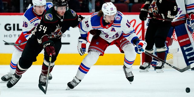 New York Rangers left wing Artemi Panarin (10) keeps the puck away from Arizona Coyotes defenseman Cam Dineen (54) as Rangers center Ryan Strome (16) looks on during the second period of an NHL hockey game Wednesday, Dec. 15, 2021, in Glendale, Ariz. The Rangers won 3-2.