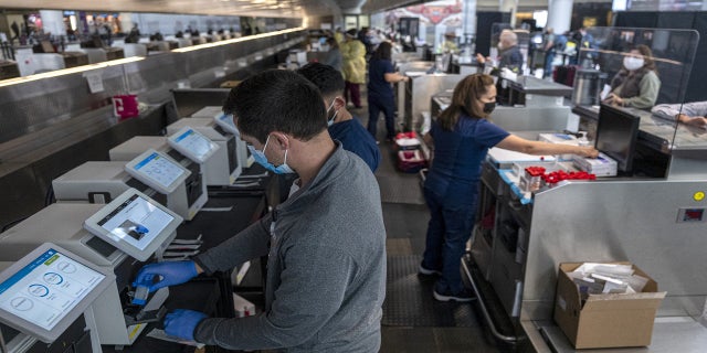 Medical workers are seen at a Dignity Health-GoHealth Urgent Care Covid-19 testing site in the international terminal at San Francisco International Airport on Dec. 2, 2021.