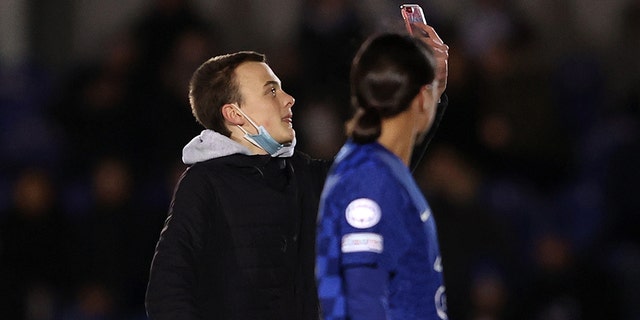 A pitch attacker tries to take a selfie with Sam Kerr of Chelsea during the UEFA Women's Champions League Group A match between Chelsea FC and Juventus at Kingsmeadow on December 08, 2021 in Kingston in Thames, England.