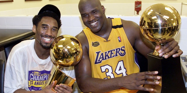 Kobe Bryant (L) of the Los Angeles Lakers holds the Larry O'Brian trophy as teammate Shaquille O'Neal holds the MVP trophy after winning the NBA Championship against the Indiana Pacers in 2000.