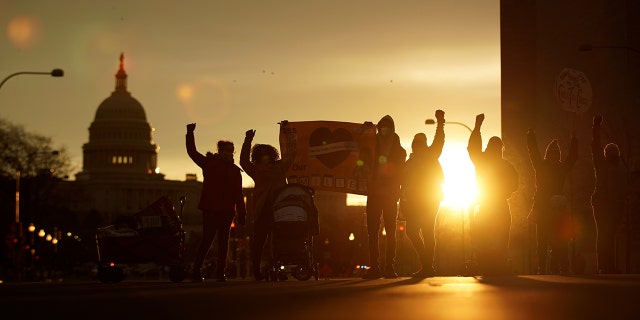 Activists blockade a street near the U.S. Capitol during a sunrise protest calling upon Congress to enact progressive legislation, in Washington, Dec. 7, 2021.