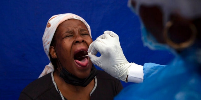 A throat swab is taken from a patient to test for COVID-19 at a facility in Soweto, South Africa, Dec. 2, 2021.  South Africa's noticeable drop in new COVID-19 cases in recent days may signal that the country's dramatic omicron-driven wave has passed its peak, medical experts say.        