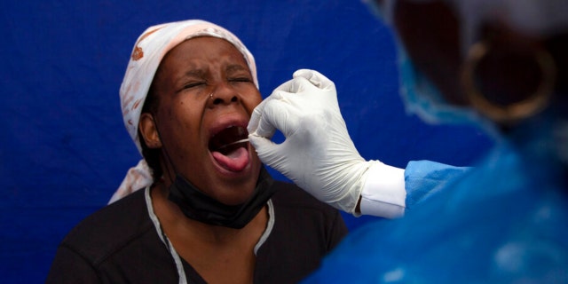 A throat swab is taken from a patient to test for COVID-19 at a facility in Soweto, South Africa, Dec. 2, 2021. South Africa's noticeable drop in new COVID-19 cases in recent days may signal that the country's dramatic omicron-driven wave has passed its peak, medical experts say.