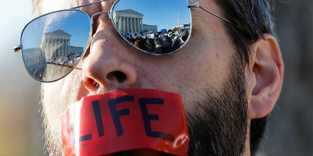 An anti-abortion activist attends a protest outside the Supreme Court building ahead of arguments in the Mississippi abortion rights case Dobbs v. Jackson Women's Health, in Washington, Dec. 1, 2021.
