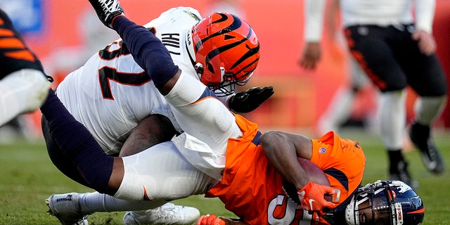 Denver Broncos quarterback Teddy Bridgewater (5) is hit by Cincinnati Bengals defensive end B.J. Hill during the second half of an NFL football game, 日曜日, 12月. 19, 2021, デンバーで. Bridgwater left the game after being injured on the play.
