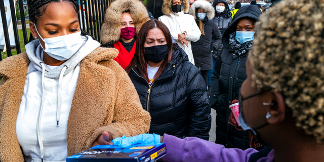 FILE - People line up and receive test kits to detect COVID-19 as they are distributed in New York on Dec. 23, 2021.