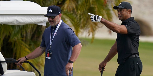 Tiger Woods, right, speaks with his trainer Kolby Wayne during a practice session at the Albany Golf Club on the sidelines of day three of the Hero World Challenge Golf tour in New Providence, Bahamas, Saturday, Dec. 4, 2021.