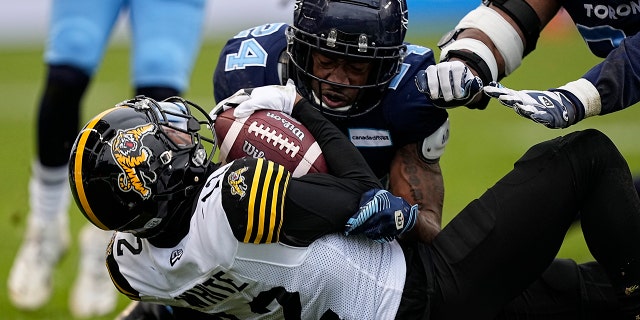 12 월 5, 2021; 토론토, 온타리오, 할 수있다; Toronto Argonauts defensive back Crezdon Butler (24) tackles Hamilton Tiger-Cats wide receiver Tim White (12) during the Canadian Football League Eastern Conference Final game at BMO Field. Hamilton defeated Toronto.