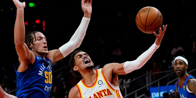 Atlanta Hawks guard Trae Young (11) goes past Denver Nuggets forward Aaron Gordon (50) during the first half of an NBA basketball game Friday, Dec. 17, 2021, in Atlanta.