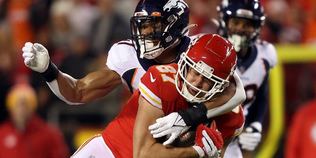 Travis Kelsey (87) do Kansas City Chiefs foi abordado por Kenny Young (41) do Denver Broncos depois que ele o agarrou durante o primeiro quarto do jogo no Arrowhead Stadium em 5 de dezembro de 2021, em Kansas City, Missouri.