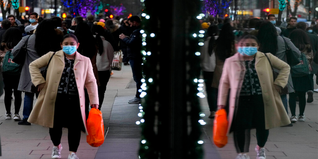 Shoppers are reflected in a window as they walk down Oxford Street, Europe's busiest shopping street, a Londra, giovedi, Dic. 23, 2021.