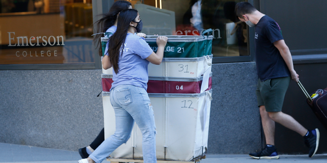 Move-in assistants push empty carts down Boylston Street as students return to Emerson College's campus in Boston on Aug. 27, 2020.