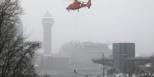 A U.S. Coast Guard rescue diver is lowered toward the vehicle lodged in the water at the brink of Niagara Falls, Wednesday, Dec. 8, 2021.