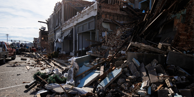 Rubble from a tornado-damaged collapsed building piles into the street on Dec. 11, 2021 in Mayfield, Kentucky.