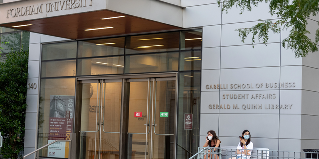 NEW YORK, NEW YORK - AUGUST 22: Students wearing masks sit outside the Gabelli School of Business at Fordham University's Lincoln Center campus. (Photo by Alexi Rosenfeld/Getty Images)