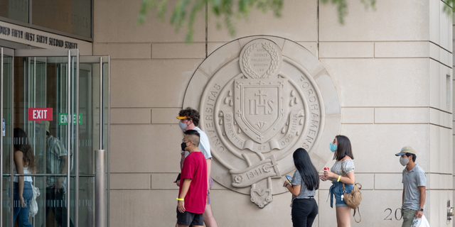 NEW YORK, NEW YORK - AUGUST 22: Students wearing masks walk into a building Fordham University's Lincoln Center campus. (Photo by Alexi Rosenfeld/Getty Images)