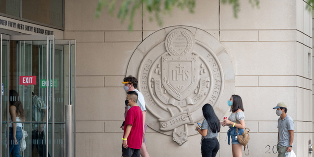 NEW YORK, NEW YORK - AUGUST 22: Students wearing masks walk into a building Fordham University's Lincoln Center campus. (Photo by Alexi Rosenfeld/Getty Images)