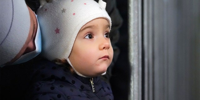 Um bebê olha para uma barraca onde uma pessoa vestindo uma roupa de Papai Noel cumprimenta crianças em uma feira de Natal em Bucareste, Romênia, sexta-feira, 17 de dezembro de 2021.