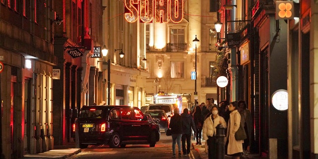 People walk in the street in Soho in London, Thursday, Dec. 30, 2021.