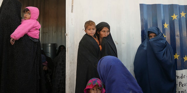 Afghan women gather outside a makeshift clinic organized by World Vision at a settlement near Herat, Afghanistan, Dec. 16, 2021.
