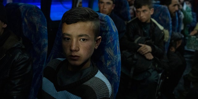 Afghans sits in a bus in Herat, Afghanistan, Tuesday, Nov. 23, 2021, for a 300-mile trip south to Nimrooz near the Iranian border.