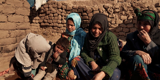 Aziz Gul, second from right, and her 10-year-old daughter Qandi, center, sit outside their home with other family members, near Herat, Afghanistan, Dec. 16, 2021. Qandi's father sold her into marriage without telling his wife, Aziz, taking a down-payment so he could feed his family of five children. Without that money, he told her, they would all starve. He had to sacrifice one to save the rest. 