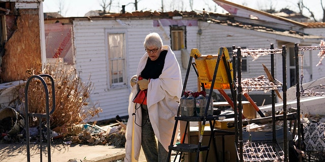 Martha Thomas stays warm with a bed comforter as volunteers help her salvage possessions from her destroyed home in the aftermath of tornadoes that tore through the region, in Mayfield, Kentucky, Monday, Dec. 13, 2021. 