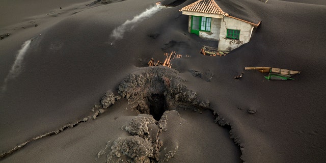 A crack is seen next to a house covered with ash on the Canary Island of La Palma, Spain, on Wednesday, December 1, 2021.