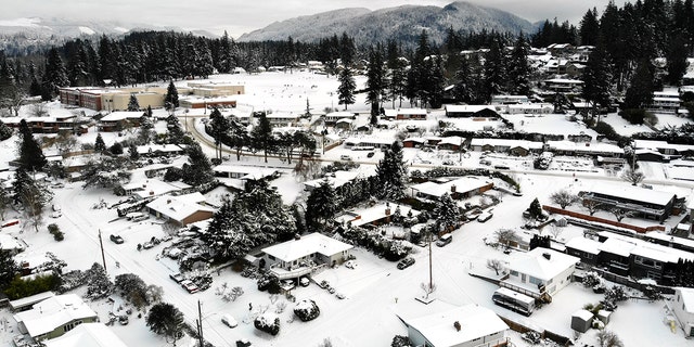 In this photo taken from a drone, snow covers streets, sidewalks and homes where nearly a foot of snow fell over the weekend, Monday, Dec. 27, 2021, in a neighborhood in Bellingham, Washington. 