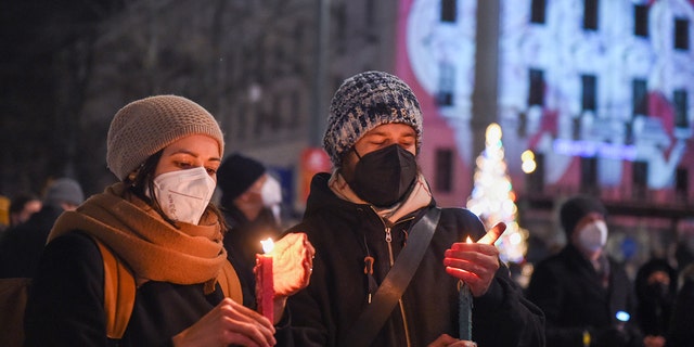 Des gens tiennent des bougies pour pleurer les victimes du COVID-19 lors d'un événement à Vienne, en Autriche, le 19 décembre 2021. 