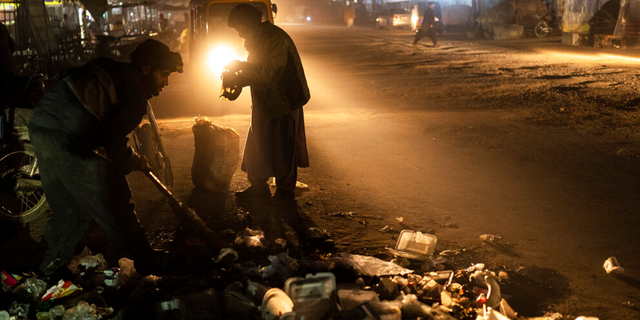 An Afghan man collects scraps of aluminum and plastic, in Herat, Afghanistan, Monday, Nov. 22, 2021. 