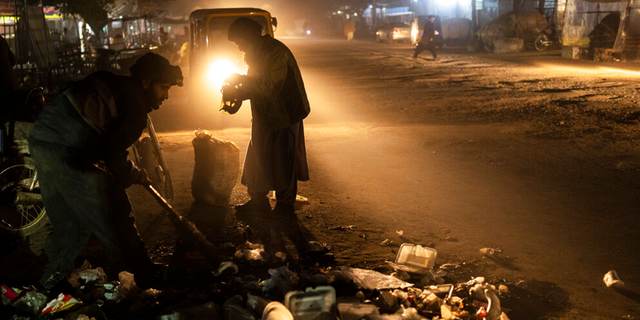 An Afghan man collects scraps of aluminum and plastic, in Herat, Afghanistan, Monday, Nov. 22, 2021.