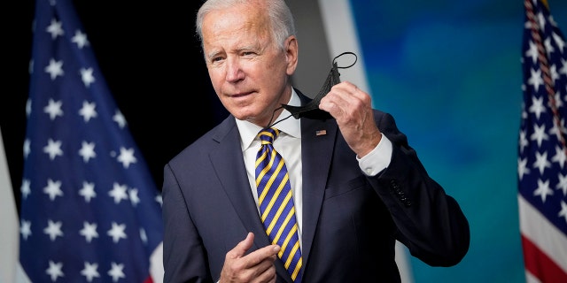 President Biden removes his face mask as he arrives to speak in the South Court Auditorium on the White House campus Oct. 14, 2021, in Washington, D.C.
