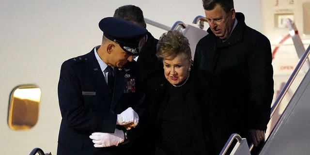 Elizabeth Dole is helped down the boarding stairs after the plane carrying her husband, former Sen. Bob Dole, R-Kan., arrived at the airport in Salina, Kan., Friday, Dec. 10, 2021. 
