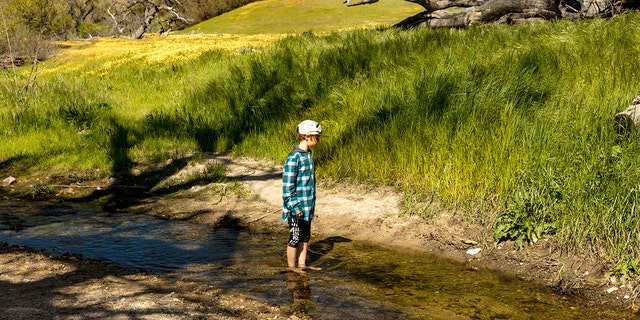 Boy in stream in San Luis Obispo County, Central California. Recently, the U.S. population growth has dipped during the first year of the COVID-19 pandemic.