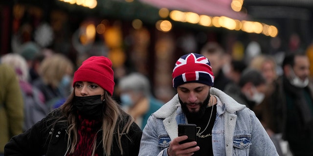 People walk past a Christmas market in Trafalgar Square in London, Wednesday, Dec. 22, 2021. British Prime Minister Boris Johnson said on Monday that his government reserves the "possibility of taking further action" to protect public health as Omicron spreads across the country.