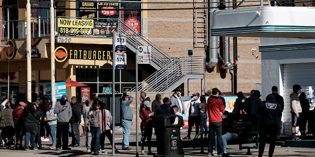 People line up for a free COVID-19 rapid test at a gas station in the Reseda section of Los Angeles on Sunday, Dec. 26, 2021, as California braces for a post-holiday virus surge.