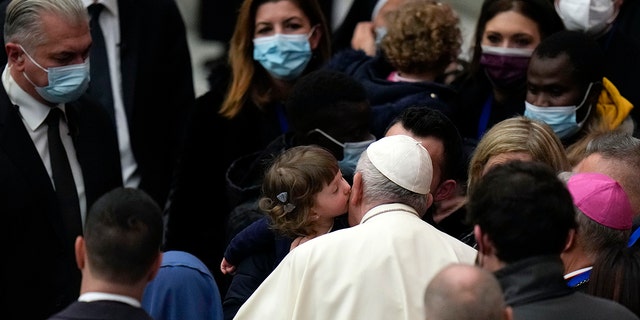 Pope Francis is kissed by a child at the end of his weekly general audience in the Paul VI Hall, at the Vatican, Wednesday, Dec. 22, 2021. 