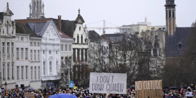 A man holds a sign which reads 'I don't drink Gluhwein' as he protests with other artists during a demonstration in Brussels on Sunday, Dec. 26, 2021. Belgian performers, cinema operators, event organizers and others joined together Sunday to protest the government's decision to close down the country's cultural life to stem the spread of the surging omicron virus variant. Gluhwein refers to a common drink which is served at Christmas markets. 