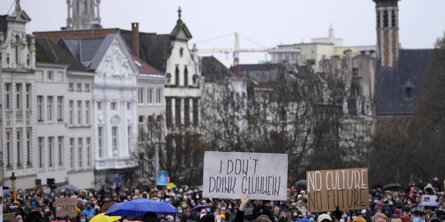 A man holds a sign which reads 'I don't drink Gluhwein' as he protests with other artists during a demonstration in Brussels on Sunday, Dec. 26, 2021. Belgian performers, cinema operators, event organizers and others joined together Sunday to protest the government's decision to close down the country's cultural life to stem the spread of the surging omicron virus variant. Gluhwein refers to a common drink which is served at Christmas markets.