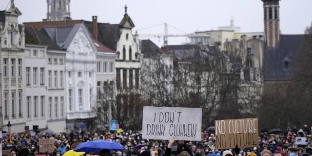 A man holds a sign which reads 'I don't drink Gluhwein' as he protests with other artists during a demonstration in Brussels on Sunday, Dec. 26, 2021. Belgian performers, cinema operators, event organizers and others joined together Sunday to protest the government's decision to close down the country's cultural life to stem the spread of the surging omicron virus variant. Gluhwein refers to a common drink which is served at Christmas markets. 