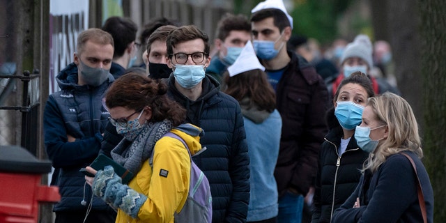 People queue outside a vaccination center in Manchester, England, Monday, Dec. 13, 2021. British Prime Minister Boris Johnson says that Britain faces a "tidal wave" of infections from the omicron coronavirus variant and he has announced a huge increase in booster vaccinations to strengthen defenses against it.  