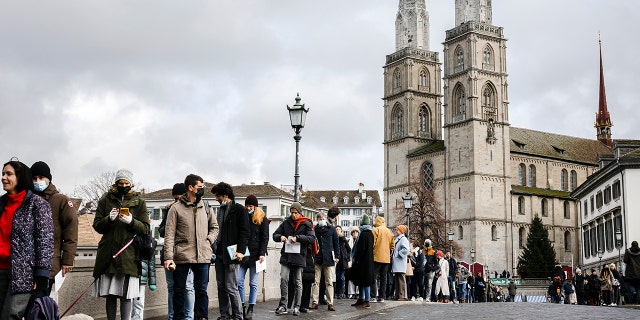 People queue from the Muenster Bridge to the Zurich City Hall to cast their ballot at the City Hall polling station to vote in a COVID-19 referendum, in Zurich, Switzerland, Sunday, Nov. 28, 2021. The coronavirus's omicron variant kept a jittery world off-kilter Wednesday Dec. 1, 2021, as reports of infections linked to the mutant strain cropped up in more parts of the globe, and one official said that the wait for more information on its dangers felt like "an eternity."  