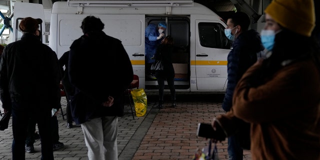 A member of the medical staff at the National Public Health Organisation (EODY) conducts a COVID-19 rapid test on a woman as others wait in a queue in Athens, Greece, Wednesday, Dec. 29, 2021.
