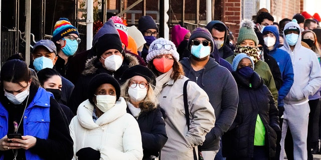 Los residentes de la ciudad esperan en una cola que se extiende alrededor del edificio para recibir kits de prueba rápida de COVID-19 gratuitos en su hogar en Filadelfia, el lunes 20 de diciembre de 2021.  