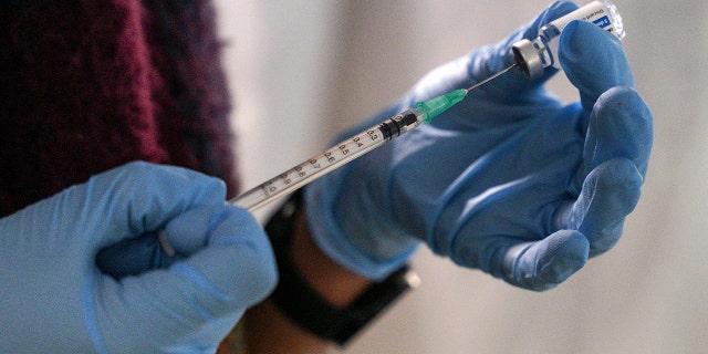 A staff member from the National Health Organisation (EODY) prepares a booster Johnson and Johnson vaccine against COVID-19 at Karatepe refugee camp,