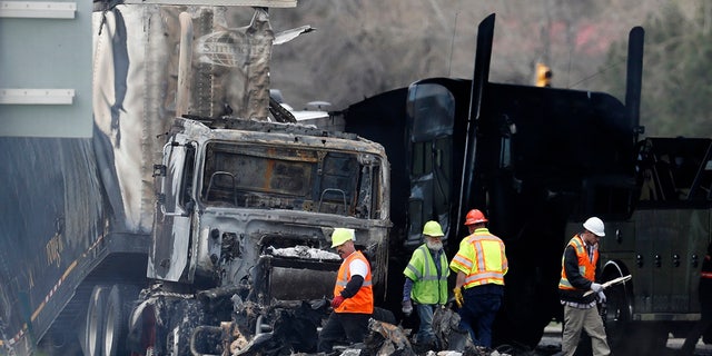 FILE - Workers clear debris from the eastbound lanes of Interstate 70 on April 26, 2019, in Lakewood, Colo., following a deadly pileup involving a semi-truck hauling lumber. A truck driver who was convicted of causing the fiery pileup that killed four people and injured six others on Interstate 70 west of Denver was sentenced Monday, Dec. 13, 2021, to 110 years in prison. Rogel Aguilera-Mederos was convicted in October of vehicular homicide and other charges stemming from the April 2019 crash. (AP Photo/David Zalubowski, File)