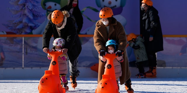 People bring their children to play during the weekend holiday outside a shopping mall in Beijing, Sunday, Dec. 26, 2021. 