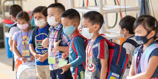 Masked students wait to go to their classroom during the first day of class at Stanford Elementary School in Garden Grove, California, on Monday, August 16, 2021. 