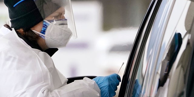 La especialista en pruebas de COVID-19 Susanna Blasko da un paso adelante con un hisopo para probar a un conductor en un sitio de prueba de coronavirus en Bellingham, Washington, el martes 21 de diciembre de 2021.   